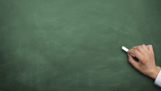 AERO: Hand with chalk about to write on an empty blackboard