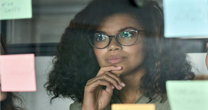 Reflective supervision: woman staring at reflective glass with postit notes.